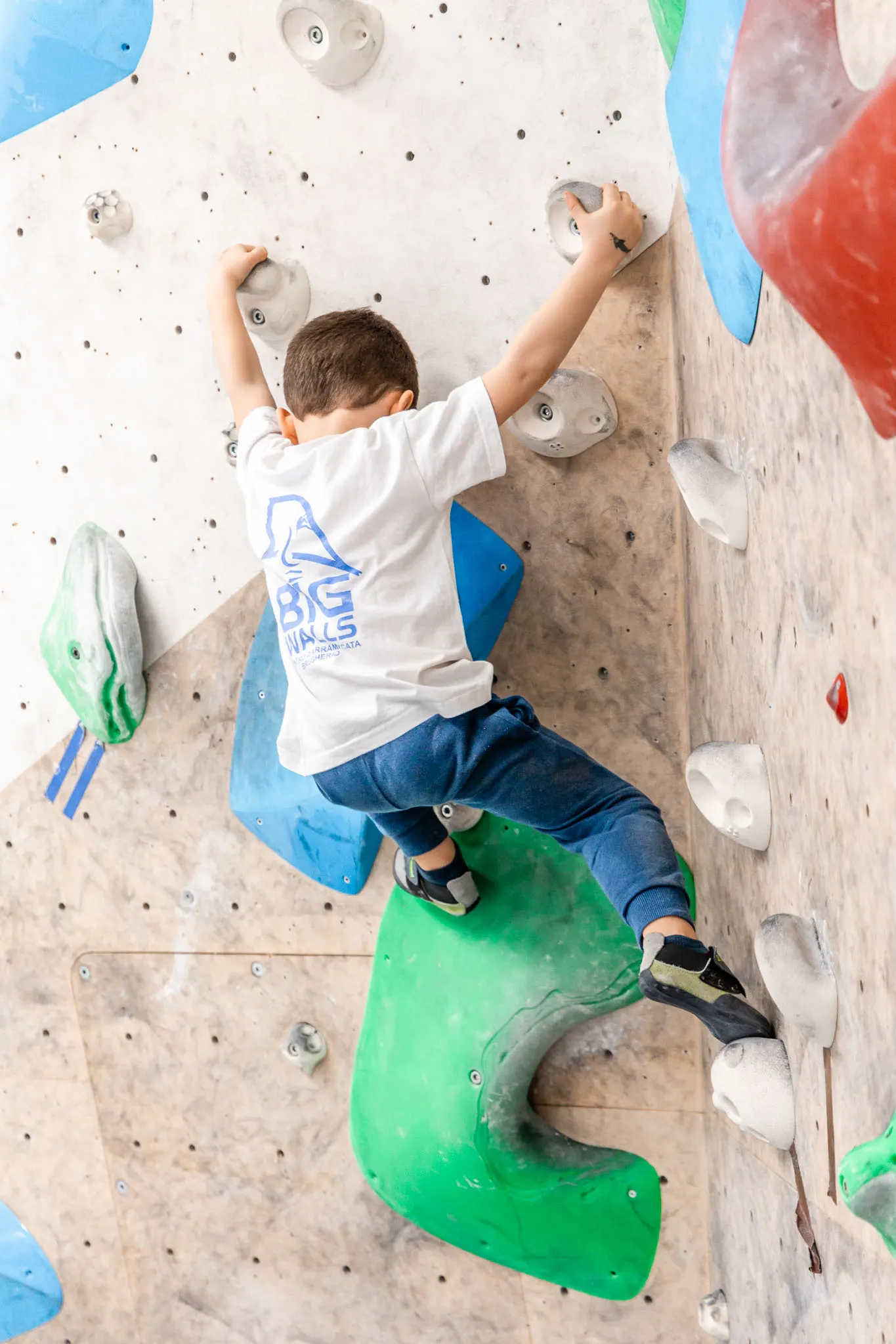 Bambino che arrampica sulla parete boulder